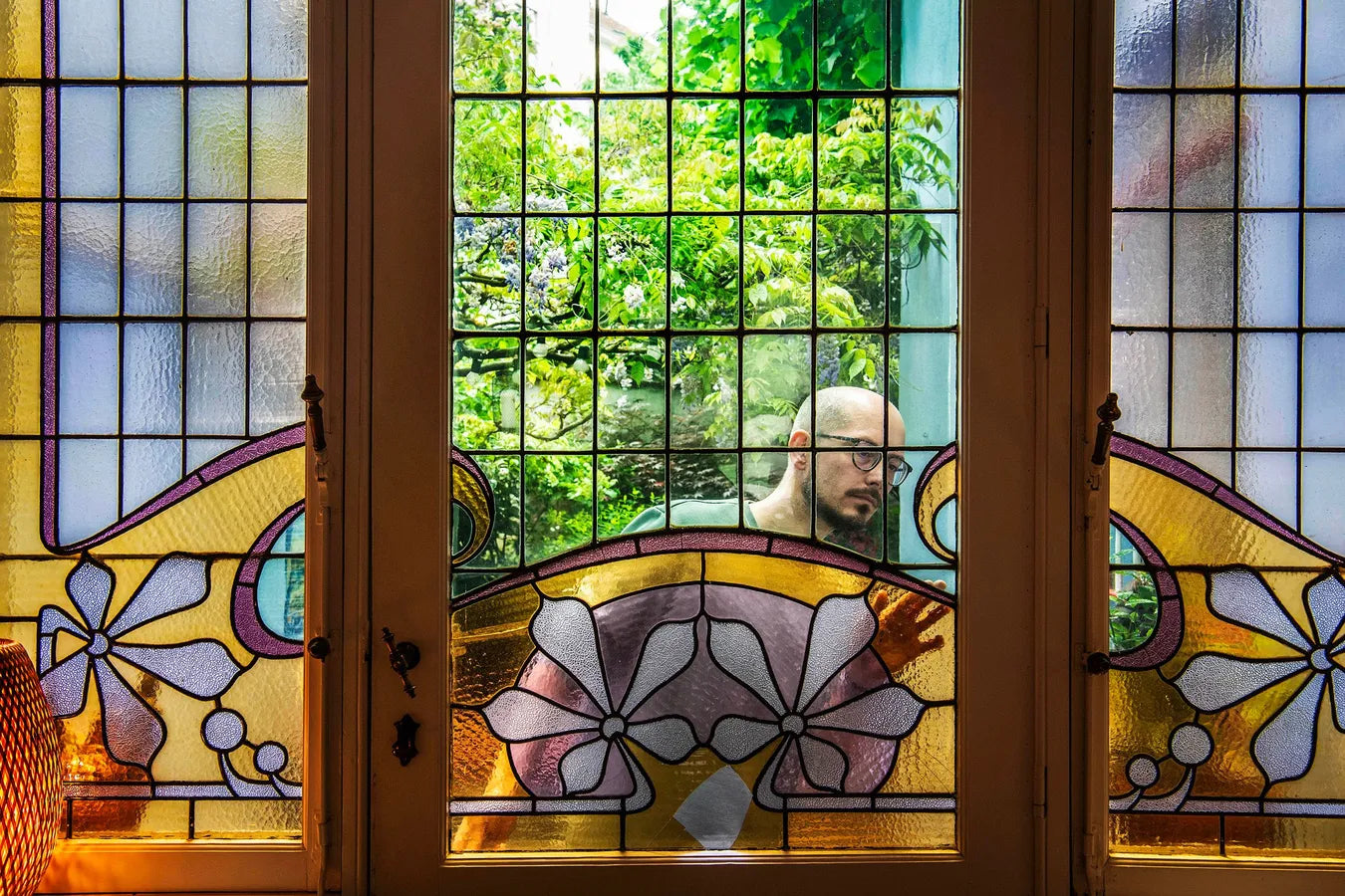 Arne inspecting stained glass damage. Stained glass in art nouveau style with bright yellow and pink floral motive.