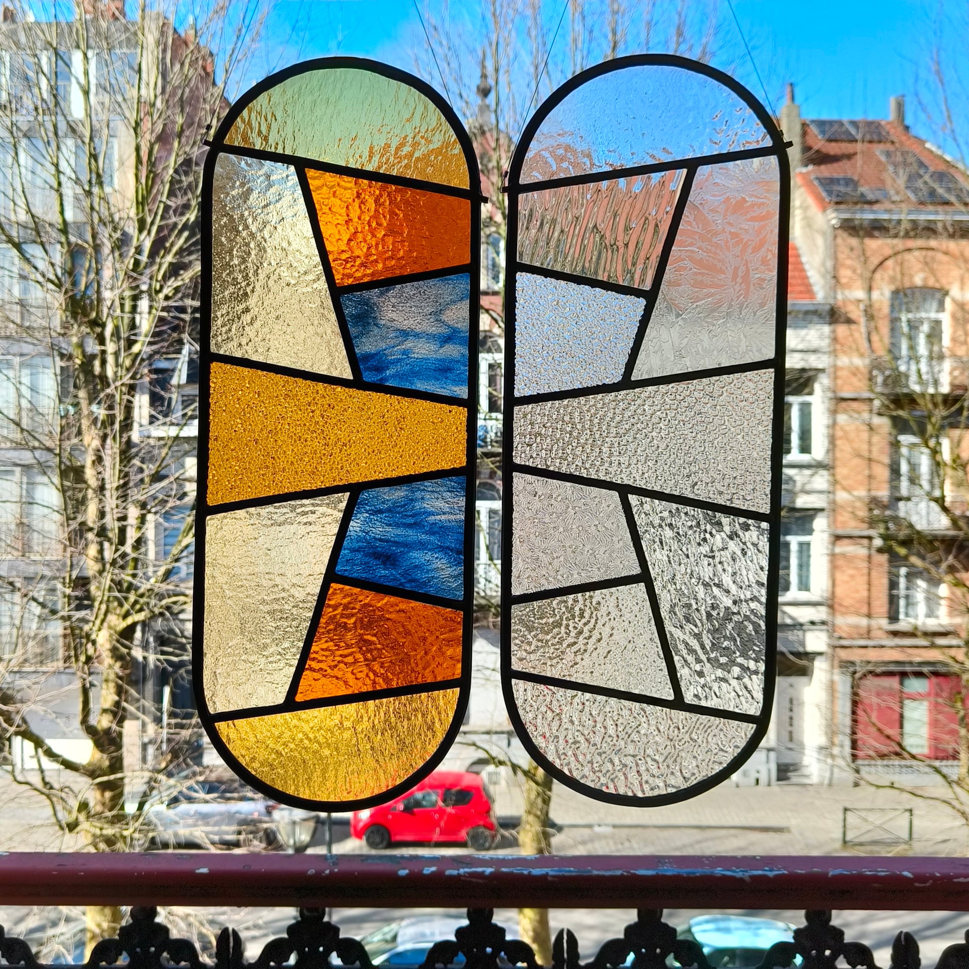 Pair of stained glass windows in different transparant structures and warm yellows with blue.