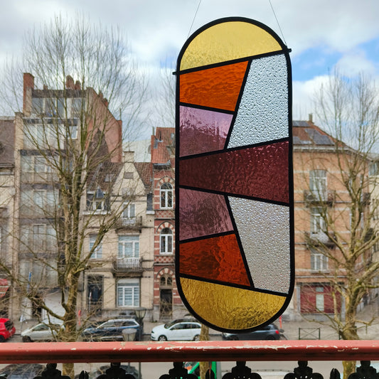 Stained glass window in warm pinks, purples and yellows with some amber glass.